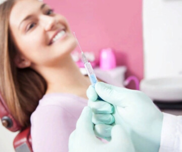 Девушка в стоматологическом кресле, врач держит шприц, Евродент фото 1